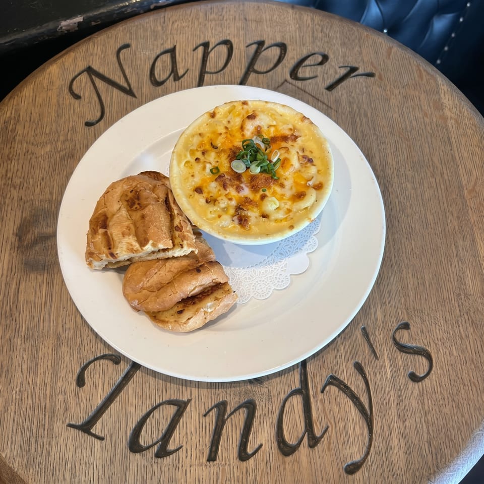 Macaroni and cheese with green onions and two pieces of bread on a white plate.